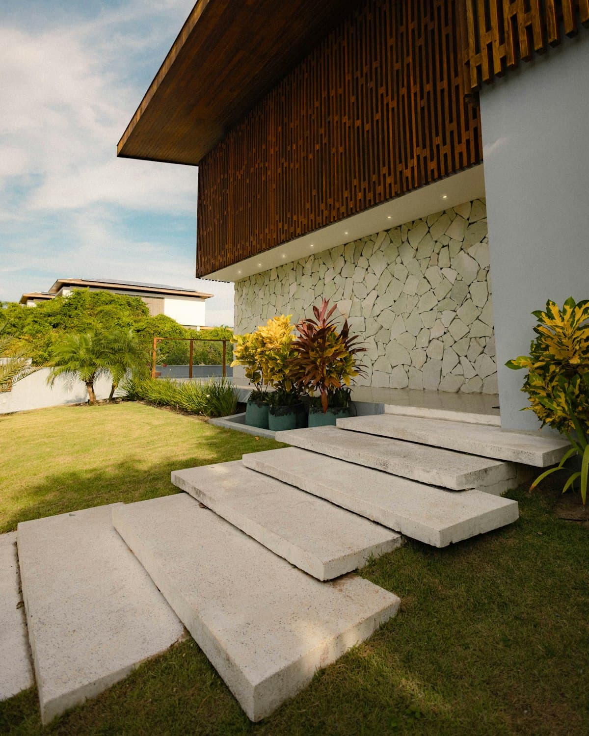 Modern home entrance with floating stone steps, lawn and layered planting